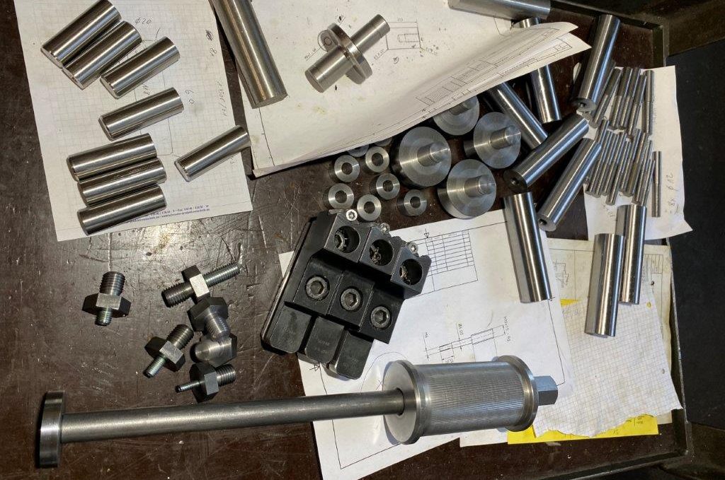 Bearbeitete Metallwerkstücke unterschiedlicher Formen auf Zeichnungen in der Werkstatt